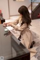 A woman in a trench coat pouring tea into a cup.