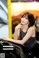 A woman sitting on top of a black car.