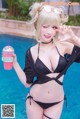 A woman in a black bikini holding a drink by a pool.