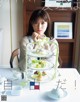 A woman sitting at a table with three tiered trays of food.