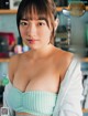 a japanese woman in a green bra top is posing for the camera