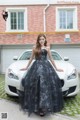 A woman in a black dress standing next to a white car.