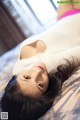 A woman laying on top of a bed in a white sweater.