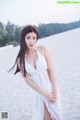 A woman in a white dress standing on a beach.