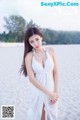 A woman in a white dress standing on a beach.