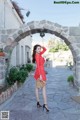 A woman in a red polka dot dress standing in an archway.