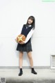 A woman in a school uniform holding a basketball.