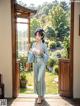 A woman in a blue kimono standing in front of an open door.