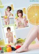 A woman in a bikini holding a lemon and a bunch of fruit.