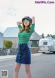 A woman in a green and white striped shirt and a denim skirt.