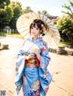 A woman in a blue kimono holding an umbrella.