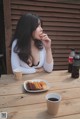 A woman sitting at a table eating a piece of food.