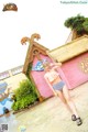 A woman standing in front of a pink building.