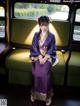 A woman in a purple kimono sitting on a green couch.