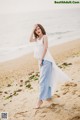 A woman standing on a beach next to the ocean.