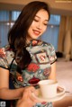 A woman sitting on a bed holding a cup of coffee.