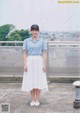 A woman in a blue and white striped shirt and white skirt.