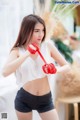 A woman in a white top and black shorts holding a red rope.