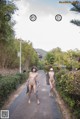 A couple of naked women walking down a sidewalk.