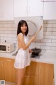 A woman in a white dress holding a wooden spoon in a kitchen.