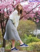 A woman standing on top of a rock in front of a tree.