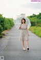 A woman walking down a road holding an umbrella.