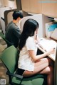 A woman sitting at a desk writing in a notebook.